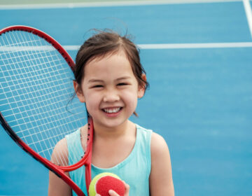 Young Asian girl tennis player on outdoor blue court